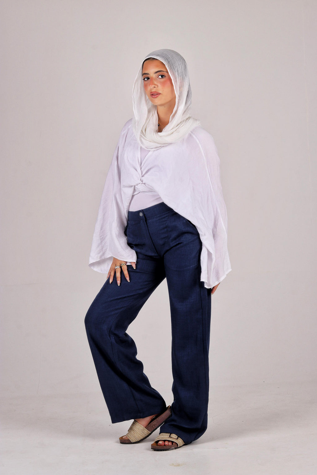a white hijab, white shirt, and navy pants