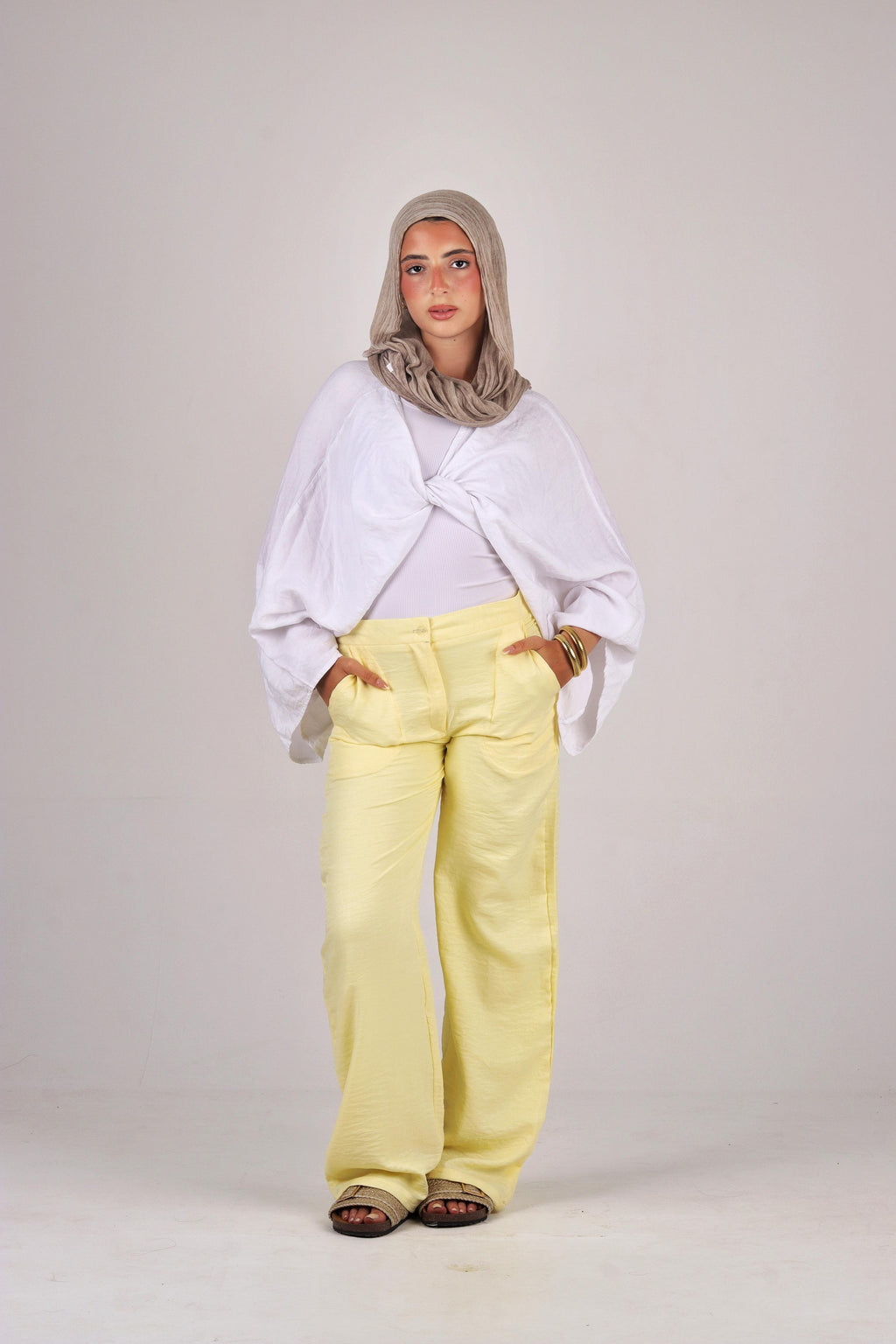 a white top and yellow pants with a gray hijab on a plain background